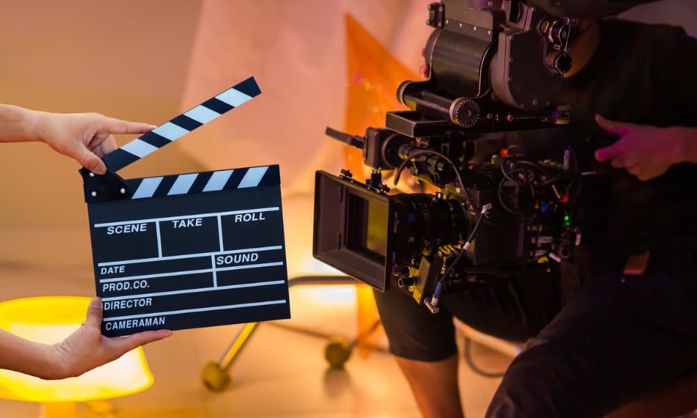 streamlined-video-production Hands holding a clapboard beside a movie camera.